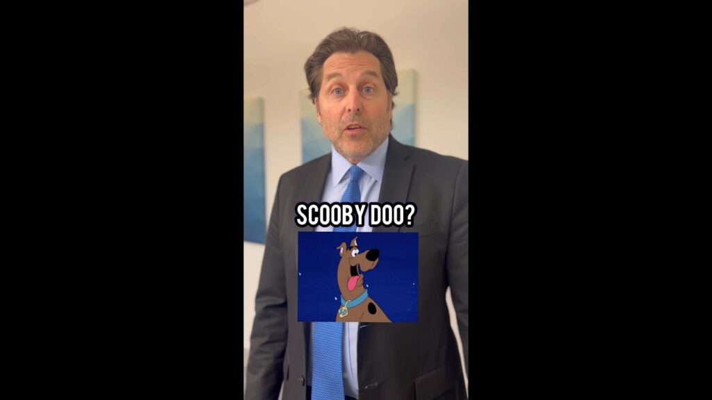 A man in a suit stands indoors with a surprised expression. Overlaid text reads "Scooby Doo?" and includes an image of the cartoon character Scooby-Doo wearing his signature blue collar.