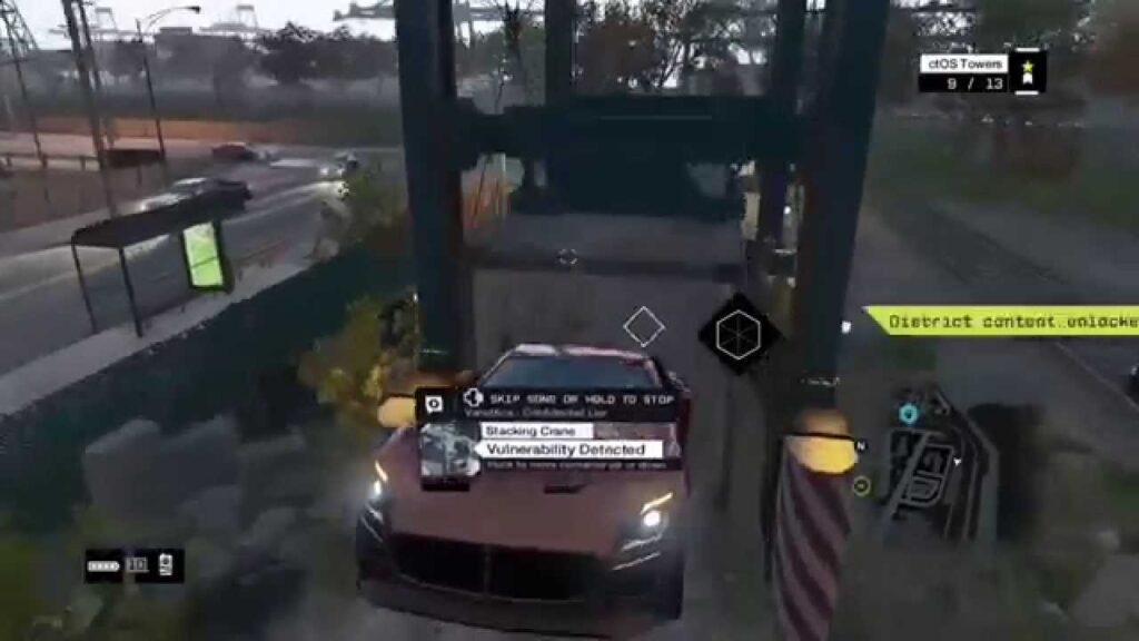 Video game screenshot showing a car suspended by a crane, with the prompt "Vulnerability Detected" and various HUD elements visible.